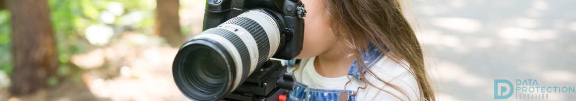 Photograph of a young girl taking a photo on a camera in a country lane. Data protection education logo is bottom left